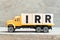 Toy truck hold letter block in word IRR Abbreviation of internal rate of return on wood background