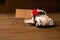 A toy white car with a heart with a piece of paper for notes on a wooden background. Creative place for text