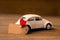 A toy white car with a heart with a piece of paper for notes on a wooden background. Creative place for text