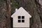 Toy wooden house on a background of tree bark. The concept is buying a house on a loan or mortgage, safe and affordable housing.