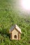 Toy wooden house on the bright grass. Sun glare on the right side. Copy space. Real estate concept.