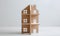 Toy wooden house on white wooden floor and bright background. Symbol of family