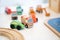 A Toy of wooden school bus drives beside a green car with many kinds of car behind