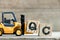 Toy yellow forklift hold letter block Q to complete word QC (Abbreviation of Quality Control)on wood background