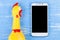 Toy yellow shrilling chicken on blue wooden background with smartphone and copy space .Template mock up for adding your design