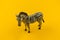 Toy zebra from plastic on a yellow background