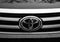 Toyota logo on a new Hilux, tree branches reflecting on the cars engine hood.