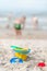 Toys at the beach - plastic yellow bucket, rake, spatula, molds on a sandy seaside beach