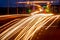 Traces of headlights from cars moving at night on the bridge, illuminated by lanterns. Abstract cityscape with highway at dusk