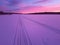 Traces of a snowmobile in the colorful frosty sunset with purple and pink colors