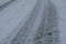 Traces on snowy road close-up. Wintertime. Blizzard. Cold weather