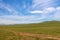 A track across a Mongolian grassland with mountains in the background