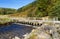 Track with bridge over river stream in mountain upland.