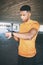 On track to peak fitness. a young man pairing his watch with a smartphone during a workout against an urban background.