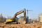 Tracked excavator working at a construction site during laying or replacement of underground storm sewer pipes.