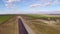 Tracked paver laying fresh asphalt pavement on an airport runway, aerial view