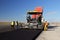 Tracked paver laying fresh asphalt pavement on a runway as part of the Danube Delta international airport expansion plan