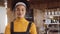 Tracking medium Close up, Female African shop owner wearing face visor standing in shop arms crossed