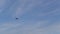 Tracking shot of helicopter flying in sunny day on background of blue cloudy sky. Remote view of helicopter hovering