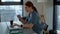 Tracking shot of overworked young female doctor in blue green medical uniform typing on laptop keyboard and rubbing eyes