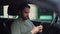 Tracking shot of serious handsome young man sitting in car, looking on display screen of cell phone.