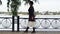 Tracking shot side view elegant relaxed senior woman strolling on river bank in park. Wide shot portrait of confident