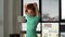 Tracking shot of sporty young woman doing stretching exercise before fitness training at home office on background of