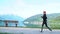 Tracking shot: woman legs in sports shoes in detail running near lake and mountains. Girl training jogging in park early morning.