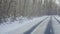 Tracking suburban empty road in snowy winter forest. The camera moves along an asphalt road on frosty sunny day. Travel