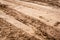 Tracks of car tires on a wet, swampy road with brown water. Country dirt road with paddles after rain