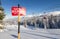 Tracks in the snow beside a ski area boundary sign.