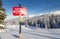 Tracks in the snow beside a ski area boundary sign.