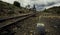 Tracks of the train next to the handle surrounded by trees under a clouded sky