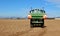 Tractor with an agricultural sprayer machine, spreads fertilizer on freshly plowed field in first spring