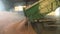Tractor arrives in the warehouse and pouring harvested wheat grain