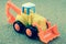 Tractor backhoe toy on sand background.