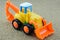 Tractor backhoe toy on sand background.