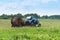 Tractor bale hay in field, blue tractor to collect hay in bales