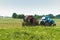 Tractor bale hay in field, blue tractor to collect hay in bales