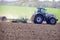 tractor on big wheels on ploughed field against green field