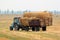 Tractor carries bales of hay on the harvested field