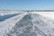 Tractor cleaning the ice on a road on a frozen reservoir in winter