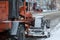 Tractor cleaning the road from the snow. Excavator cleans the streets of large amounts of snow in city. Workers sweep