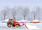 A tractor cleans the road in the city after heavy snow and hail. parked cars on the street in snowdrifts and snow