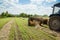 Tractor collects dry hay on the farm field