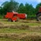 The tractor collects dry hay in the field, the hay presses the bale press, work in the field