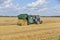 The tractor collects straw in large bales in the field.