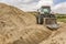 Tractor constructing a water pipeline ditch at road construction works