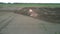 Tractor cultivates soil with harrow at farmland aerial view