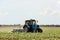 Tractor cultivating field of ripening sunflowers. Agricultural industry